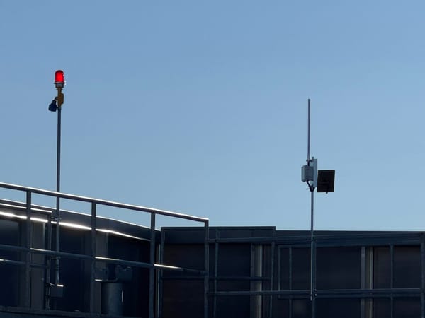 Image of a repeater sited on the rooftop of a sky scraper adjacent to an aircraft warning light.